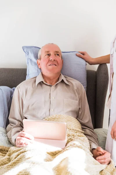 Velho Doente Homem Deitado Uma Cama Segurando Tablet Nas Mãos — Fotografia de Stock