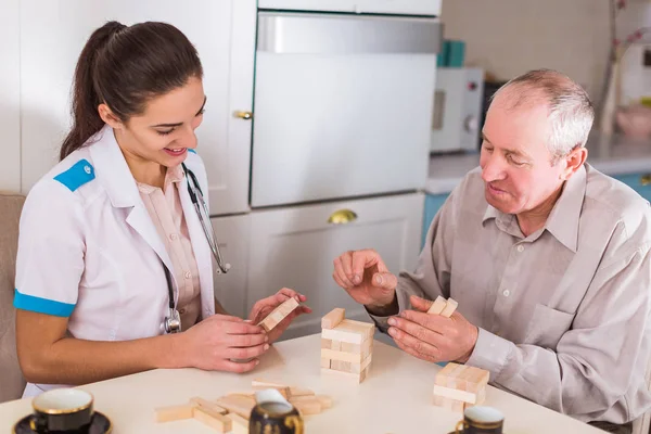 Der Junge Lächelnde Arzt Sitzt Mit Dem Alten Kranken Tisch — Stockfoto