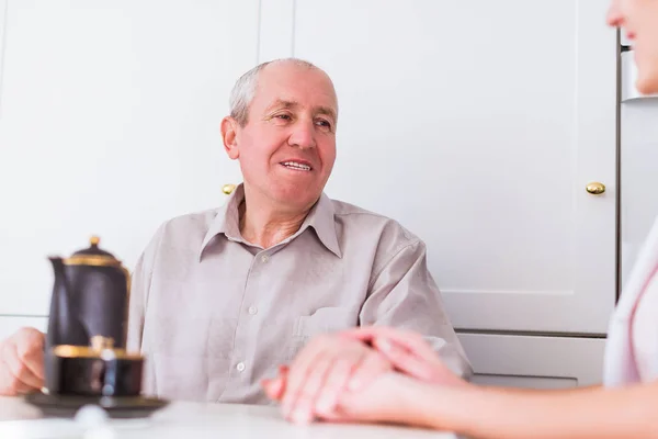 Velho Homem Feliz Sentado Mesa Cozinha Segurando Mão Jovem Enfermeira — Fotografia de Stock