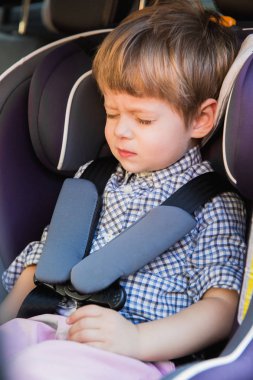 Kim bir araba bebek araba koltuğuna oturan ve gözleri göz kırpıyor kapalı gözlerle sevimli küçük çocuk portresi