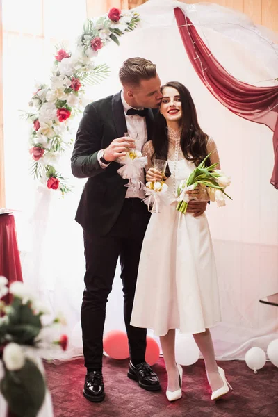 登記所と婚約者の結婚式の日に彼の花嫁をキスで美しい若いカップルの立っています — ストック写真