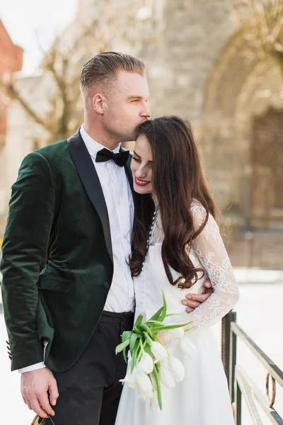 婚約者の花嫁をキスと抱擁で屋外に立っているロマンチックな若いスタイリッシュな新婚夫婦 — ストック写真