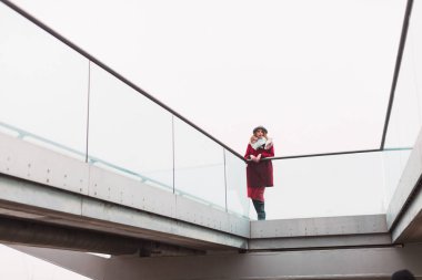 Genç zarif büyüleyici Bayan köprüde açık ve parmaklıklar güvenerek ayakta