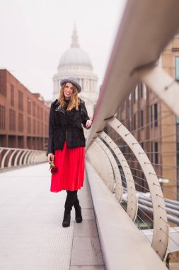 Köprünün üzerinde açık duran ve kırmızı tutan şapkalı genç şık çekici kadın elinde gül