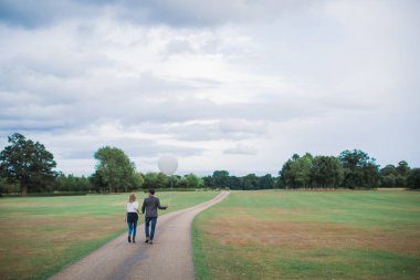 Kim yol ve balon elinde tutan erkek üzerinde yürüme arkadan görünüşü aşık genç mutlu romantik çift