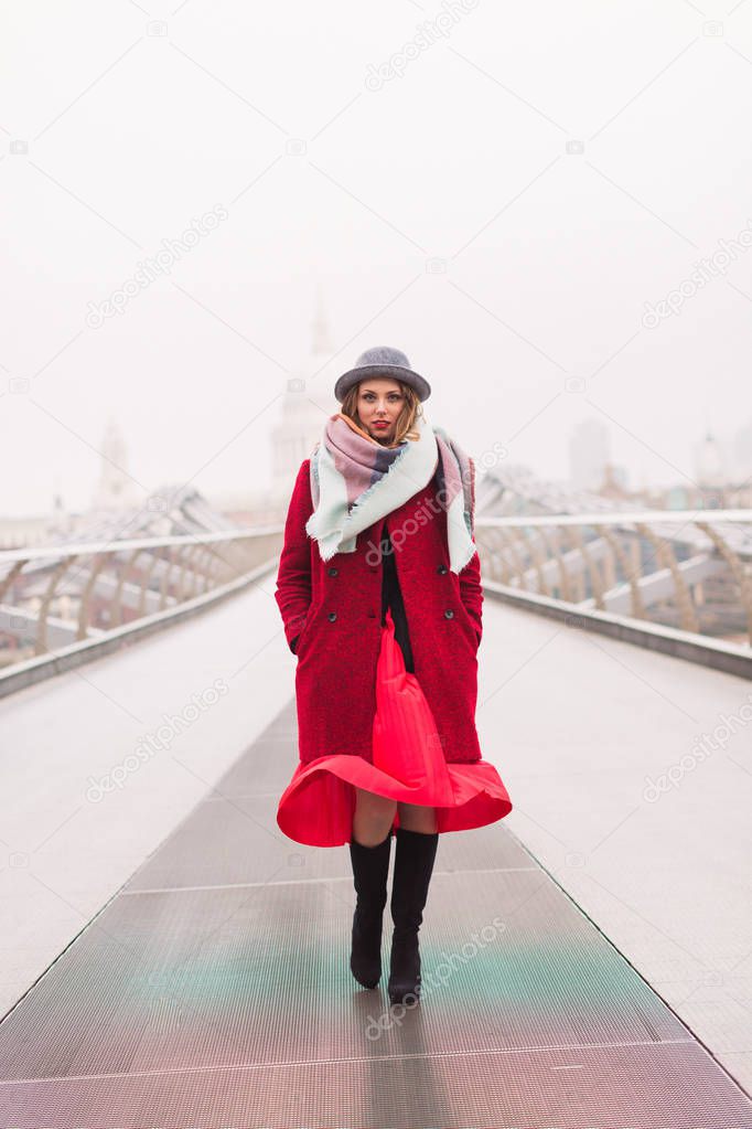 The young elegant attractive lady standing on the bridge outdoors