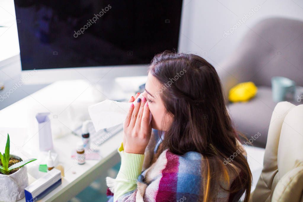 Top view of the young sick woman who sitting in the office and wiping the nose