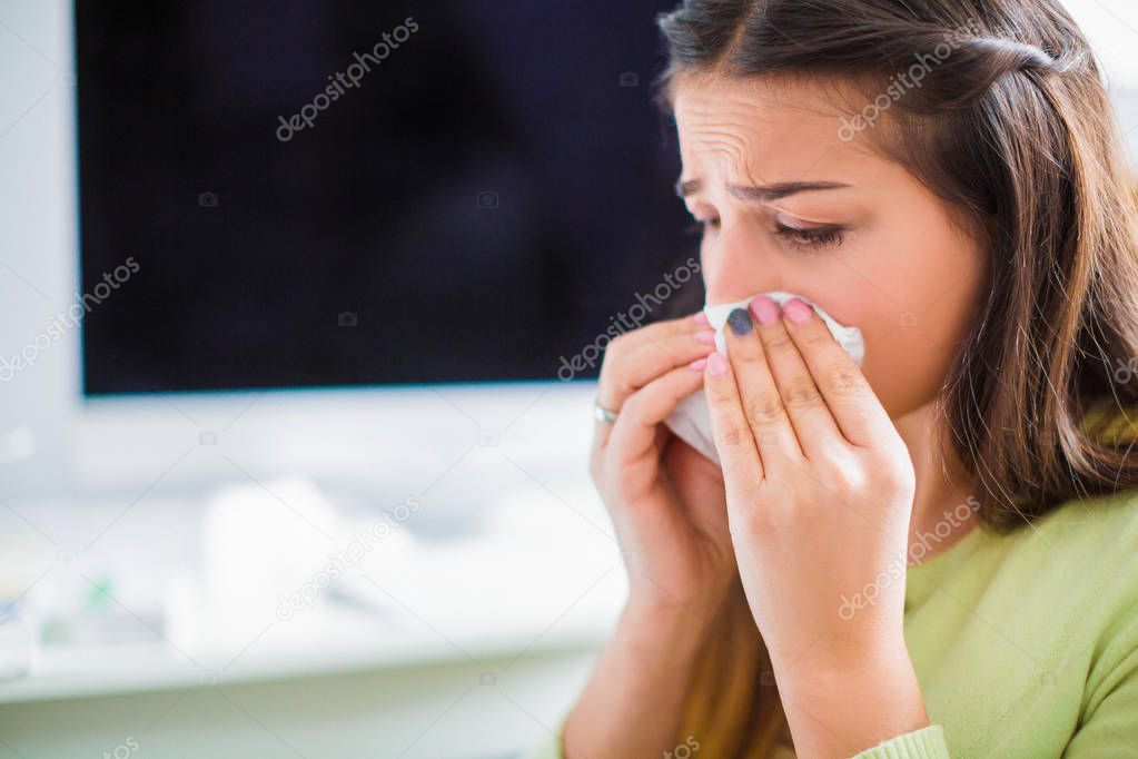 Side view of the young sad sick woman who sitting in the office and wiping the nose