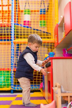 Oyuncak mutfak ile oyun odasında oynarken küçük şirin çocuk