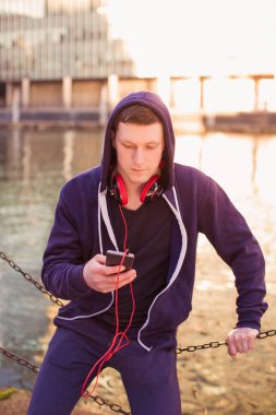 Genç sportif adam kulaklık açık oturma ve telefonu kullanma