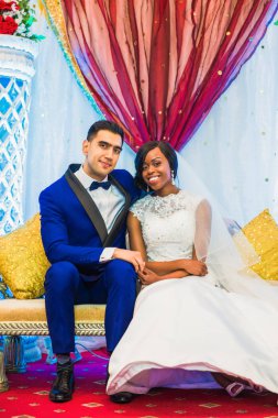 Kapalı kucaklama içinde kanepede oturan genç romantik yeni evliler