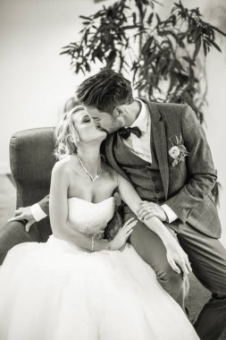 Kucaklama restoranda bir sandalyede oturan ve öpüşme genç mutlu romantik yeni evliler