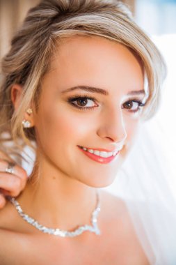 Genç güzel gülümseyen gelin, annesi kızının kapalı boynundaki kolye giyinmeye portresi