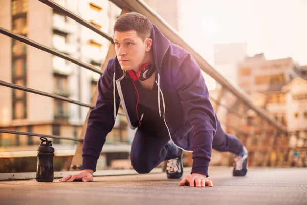 The young concentrated sporty man doing push-ups outdoors