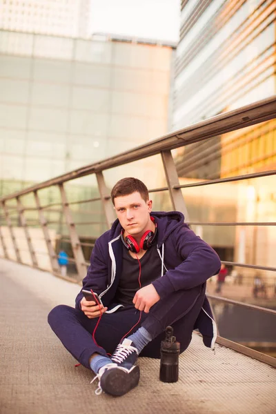 Jovem Desportista Sentado Chão Livre Segurando Telefone Mão — Fotografia de Stock