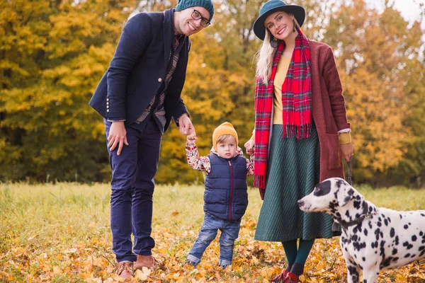 The young happy family standing in the park with their friend dalmatian dog