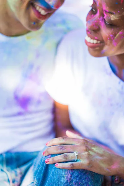 Portrait of the young couple in love with paints on their faces who sitting outdoor and smiling