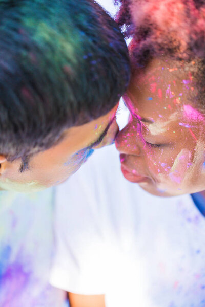 Close-up the young couple in love with paints on their faces sitting face to face outdoors