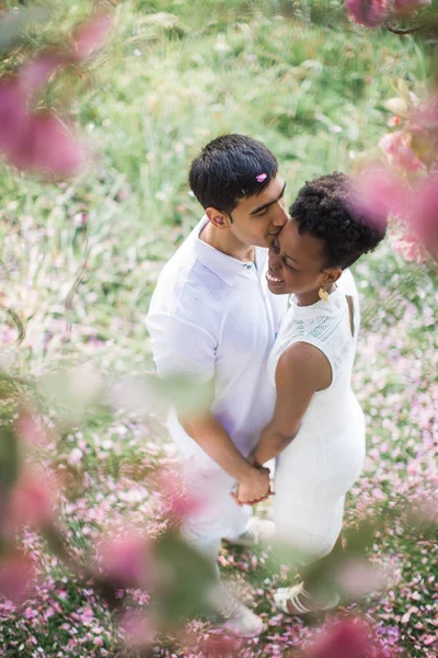 相爱的年轻夫妇站在公园里的树下 互相牵着手 男人亲吻女人 — 图库照片