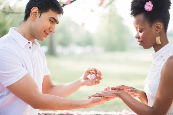 幸せな若者を保持している結婚指輪と公園で幸せな女の手で花の側面図 — ストック写真