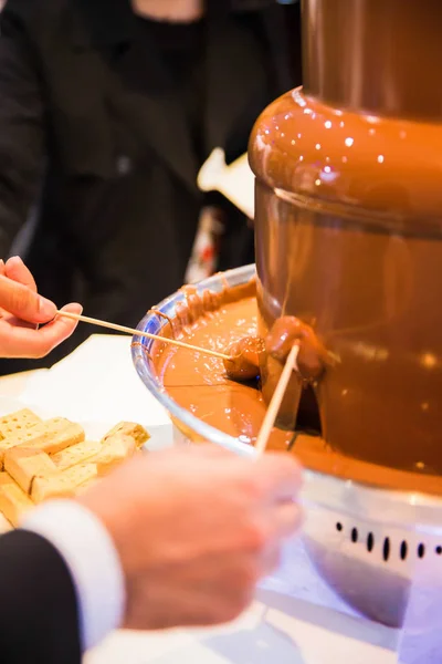 Photography of chocolate fountain which people eating indoors