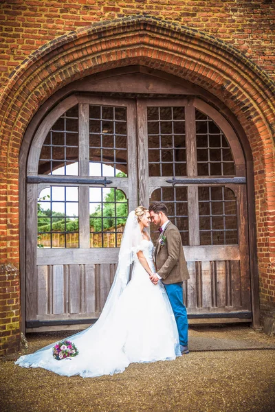 年轻浪漫美丽的新婚夫妇站在门前面对面的建筑户外和牵手 — 图库照片