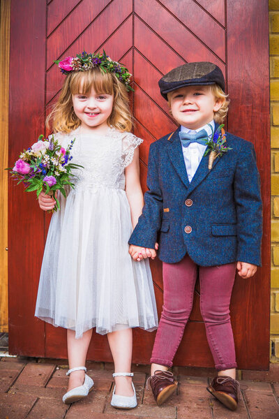 The little cheerful beautiful girl and boy standing near the door together