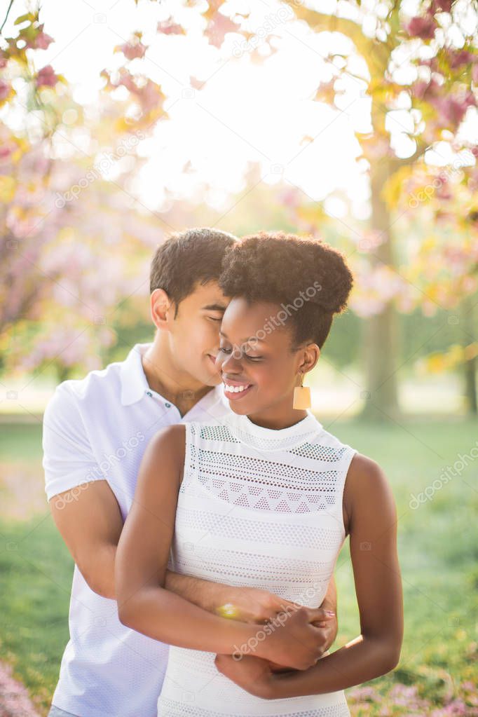 Portrait of the young romantic couple who standing in embrace in the park and smiling