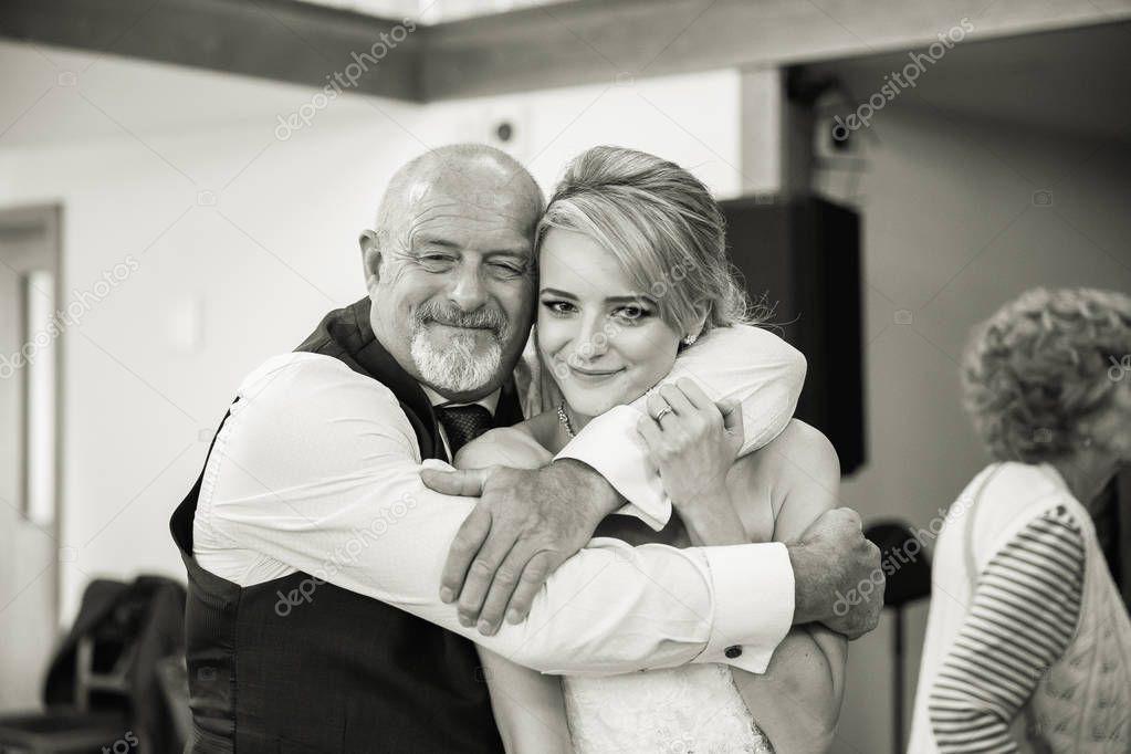 The happy father embracing the young happy bride in the restaurant