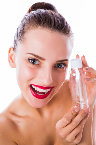 Close-up cheerful, smiling woman keeps empty bottle in hands near her face on the white background