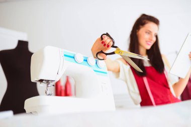 ön plan makas hangi terzi tutar ve tablet arka planda çalışma şeyler ile donatılmış atelier karşı bakar