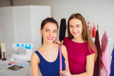 İki neşeli kadın portresi, bunlardan biri istemcisinde atelier için bant kullanarak ölçüleri alır terzi