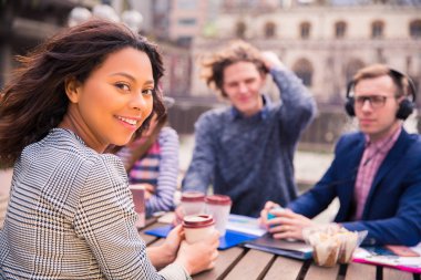 Pozitif öğrenciler sit yiyecek ve hepsi ile klasörler ile kahve fincan ile ara zamanında kulakları açık havada kulaklık müzik dinler