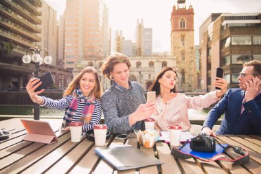 Mutlu genç öğrenciler oturup selfie-fotoğraf üstünde onların telefon ara, açık havada zamanında