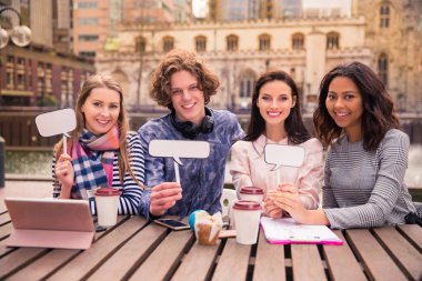 Mutlu gülümseyen öğrenciler oturmak ve tablet bir ara, açık havada zamanında onların elinde tutmak
