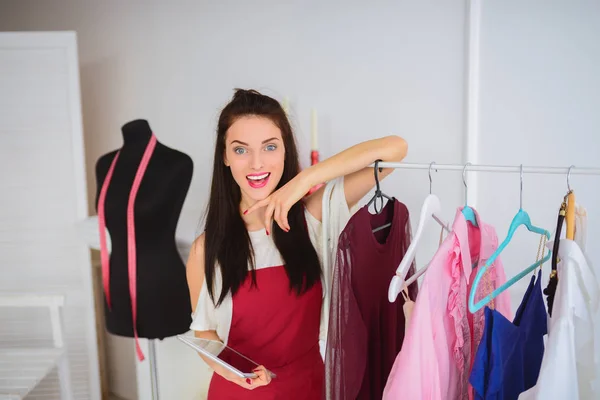 Smiling Delighted Young Seamstress Stands Own Clothes Collection Keeps Tablet — Stock Photo, Image