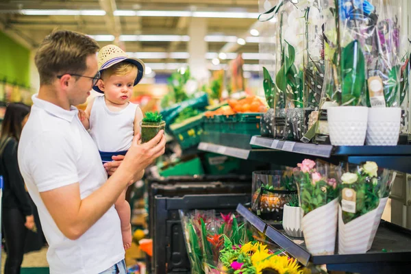 父が店で幼い息子を保持し 彼らは植木鉢を選択 — ストック写真