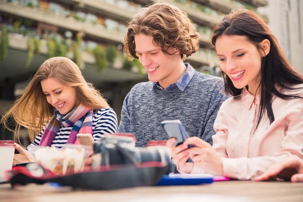 Des Étudiants Souriants Joyeux Assoient Regardent Leur Téléphone Pendant Une — Photo