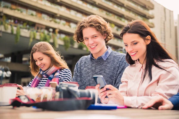 Ciekawe Uśmiechający Się Studenci Siedzą Swoich Telefonach Czasie Przerwy Zewnątrz — Zdjęcie stockowe