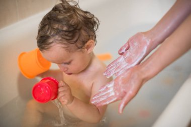 Kapalı su ile banyo oturan küçük bir çocuk olacak üst jel ile ellerinizi yıkayın