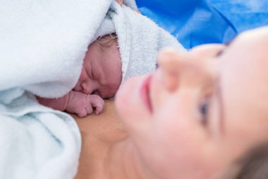 Mutlu anne kapalı yakın çekim yeni doğan bebek bir havlu ile sarılmış yatıyor