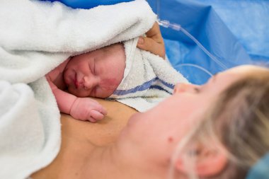 Bebeğe kapalı görünüyor anne üzerinde yakın çekim yeni doğan bebek bir havlu ile sarılmış yatıyor