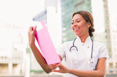 Klasör tutar ve açık havada, baktığı mutlu genç kadın doktorun yakın çekim yan