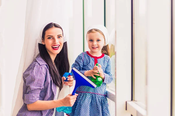 屋内で彼女の娘と一緒に Windows を洗う若い幸せな主婦の肖像画 — ストック写真