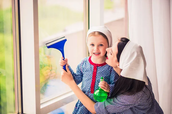 若い陽気な主婦が屋内でかわいい娘と Windows を洗う — ストック写真