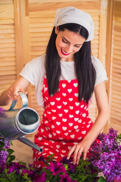 若い美しい主婦自宅じょうろの助けを借りて 植木鉢を水します — ストック写真