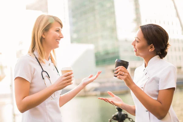 Duas Enfermeiras Sorridentes Ficam Com Xícaras Café Contam Umas Com — Fotografia de Stock