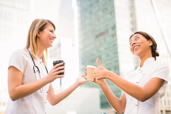 Duas Belas Enfermeiras Sorridentes Guardam Xícaras Café Contam Umas Com — Fotografia de Stock