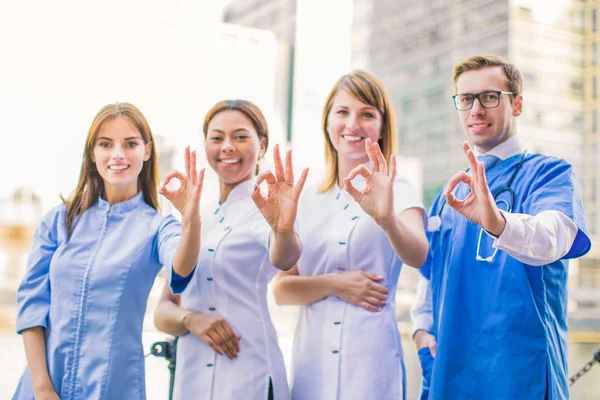Grupo Jovens Trabalhadores Médicos Sorridentes Está Juntos Mostra Sinal Mãos — Fotografia de Stock
