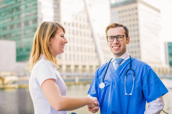 Twee Jonge Gezondheidswerkers Schudden Hun Handen Glimlach Buitenshuis — Stockfoto